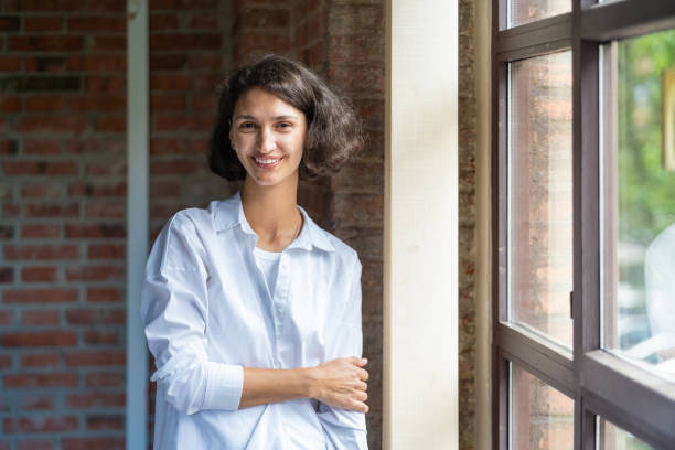 istock Happy businesswoman smiling while standing in office window light 2179322343
