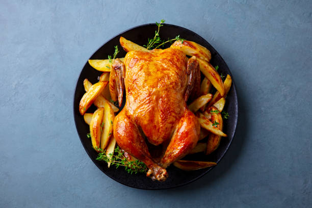 istock Roasted chicken with potatoes on dark plate. Grey background. Close up. Top view. 2179327823