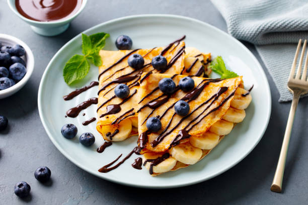 istock Crepes, thin pancakes with chocolate sauce and fresh blueberries. Grey background. Closeup. 2179329164