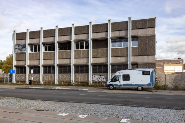 Vacant office building ready for demolition with a parked camper van in front