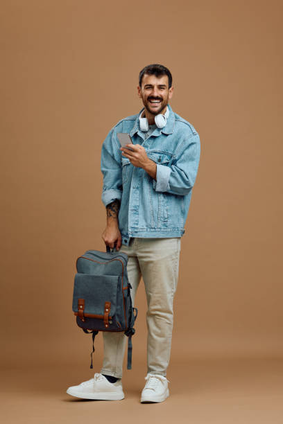 istock Studio shot of happy man with backpack and cell phone looking at camera. 2179342082