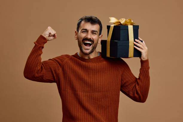 istock Cheerful man celebrating while holding gift boxes on his shoulder and looking at camera. 2179342449