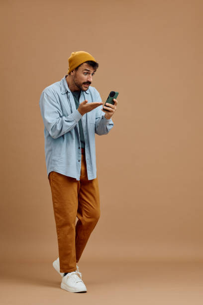 istock Man in disbelief using cell phone against neutral background. 2179342808