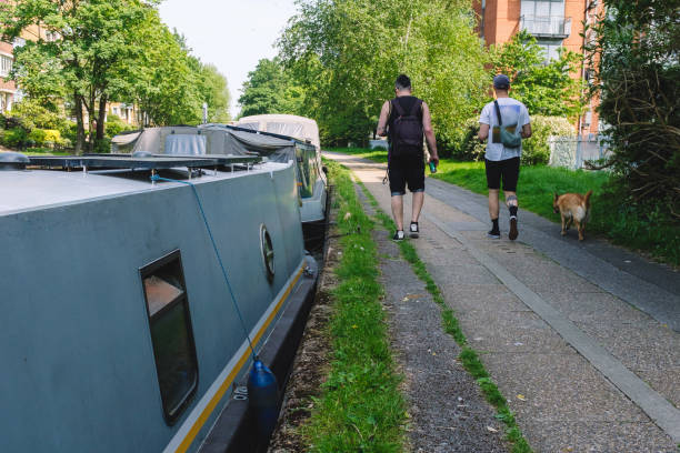 istock Two Men and a Dog Walking Alongside Canal Boats 2179352961