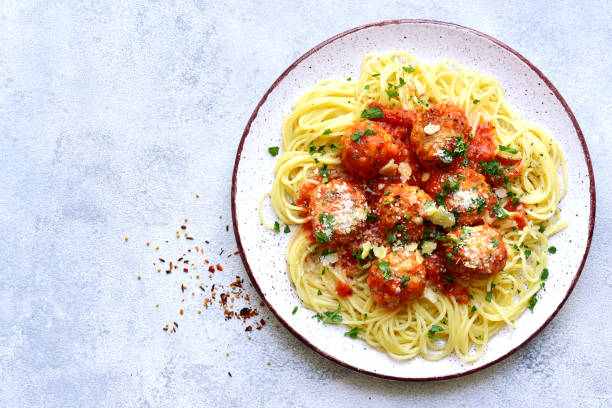 Pasta spaghetti with meat ball in tomato sauce on a plate over light grey  slate, stone or concrete background. Top view with copy space.