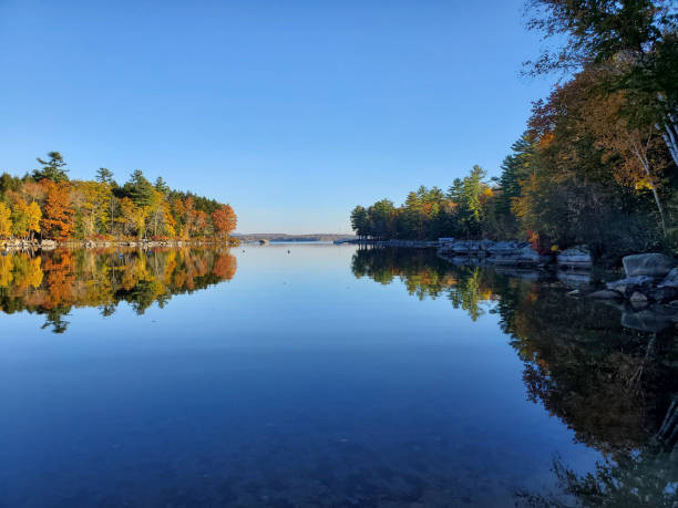 New Hampshire horizon reflection in a still calm lake with colorful leaves turning
