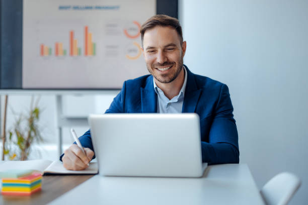 istock Smiling businessman working on laptop in office. 2179415498