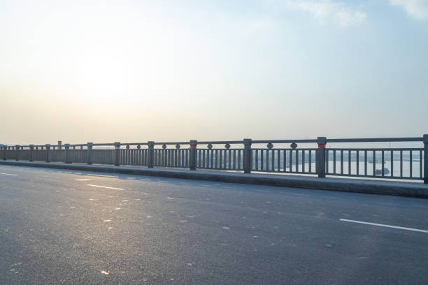 Empty asphalt Bangladeshi riverside bridge road in sunset time with blue cloudy winter sky with sun ray. New modern highway concrete construction. Concept of way to success. Transportation logistic