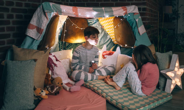 istock Kid making terror gesture illuminated with lantern while little scared girl cover face with hands 2179416370