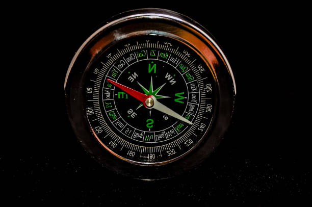 A compass with a red needle pointing to the north. The compass is black and silver