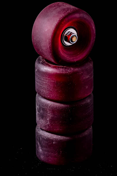 Four skateboard wheels stacked on top of each other. The wheels are red and appear to be worn