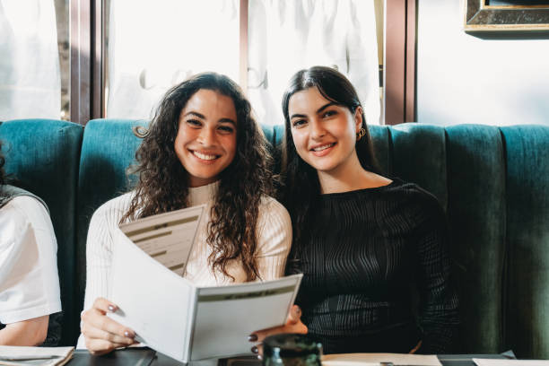 istock Two young women smiling and reading a menu in a restaurant 2179420938