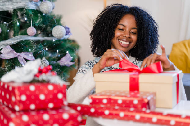 istock Woman wrapping christmas presents under tree having fun 2179425894
