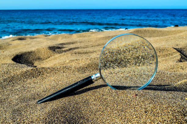 istock A magnifying glass is on the sand at the beach 2179430396