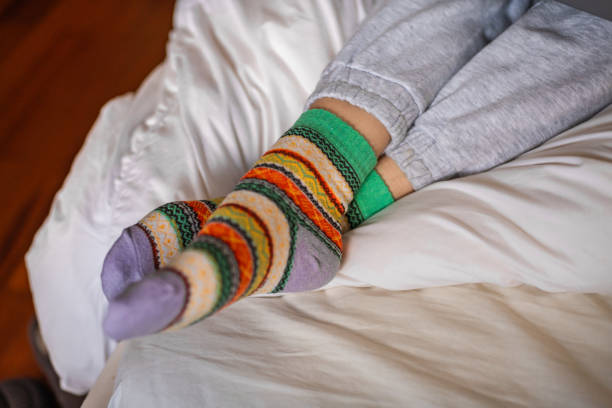 istock Women's feet in warm colored socks on a bed, close up 2179431373