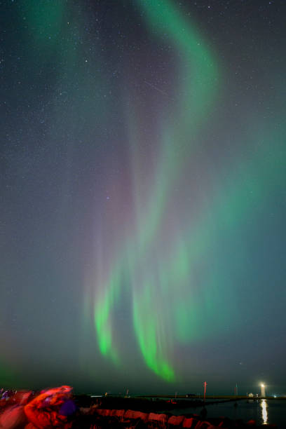 Aurora borealis mountains during a starry atumn  night as onlookers  view the phenomena.
