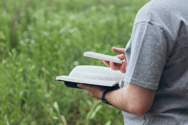 istock A man with a smart phone and a Bible in his hands outside. 2179437126