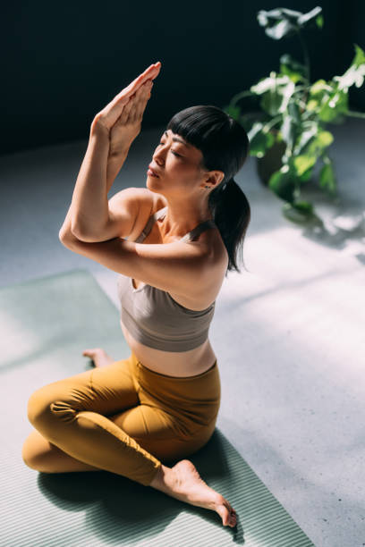 istock Peaceful Woman Practicing Yoga Meditation on Mat in Sunlit Room 2179438438
