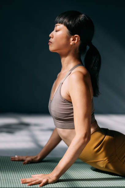 istock Young Woman Practicing Yoga on a Mat in Sunlit Room 2179438456