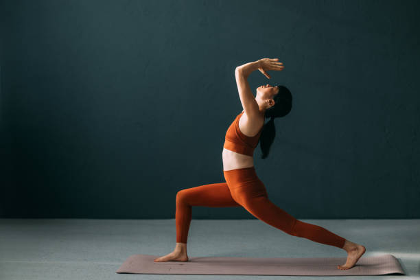 istock Woman Practicing Yoga in Warrior Pose on Yoga Mat 2179438467