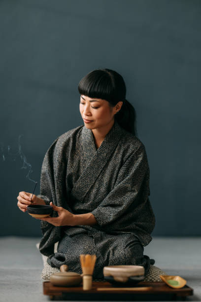 A serene moment as a woman in traditional attire performs a tea ceremony. The setting exudes calm and cultural elegance with attention to detail in the ceremonial setup.