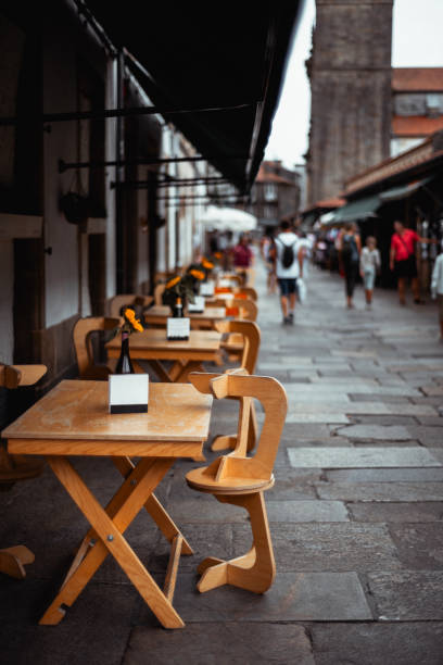 Pedestrian zone, street view , sidewalk cafe, stone arches, old town Santiago de Compostela, Galicia, Spain. Couple passing by.