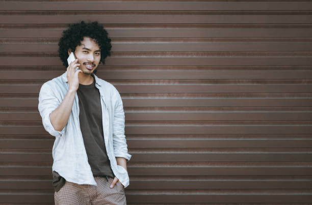 istock Man talking on phone by brown wall 2179465945