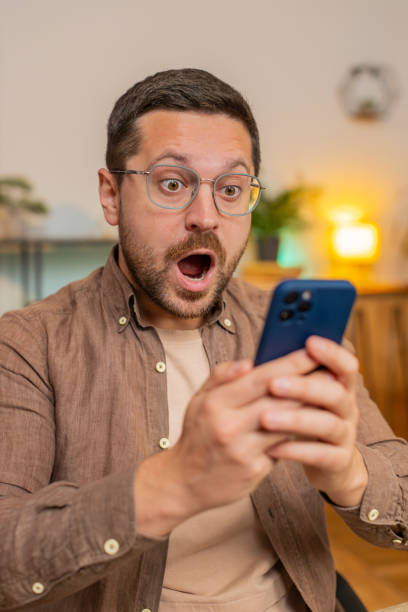istock Caucasian young man guy using smartphone shocked by sudden victory sitting in home office room 2179469770