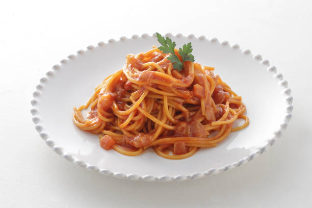 Pasta, portion of spaghetti noodles with grated cheese on a white plate on a green and white checkered tablecloth. Top view.