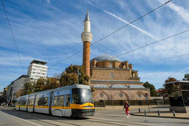 Sofia, Bulgaria - October 17, 2024: A tram passes in front of the Banya Bashi Mosque in Sofia, Bulgaria.