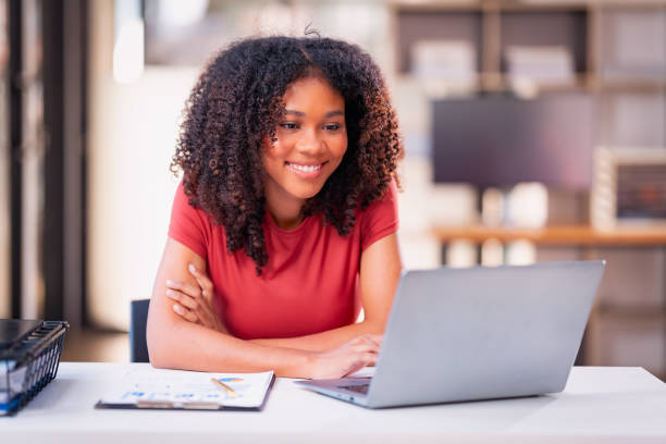 istock Beautiful professional woman sitting at table smiling while reading important documents with financial graphs and accounting of company. 2179509508