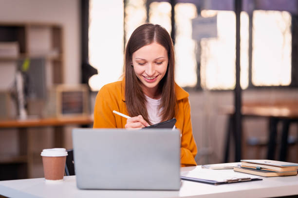 istock Beautiful professional woman sitting at table smiling while reading important documents with financial graphs and accounting of company. 2179509524