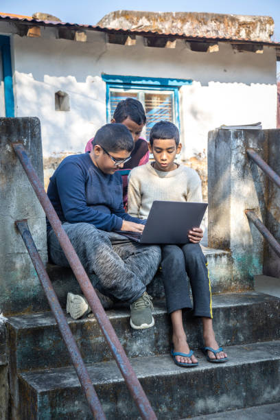 istock Indian villages kids Using a Laptop on a Concrete Staircase in a Rural Setting 2179510389