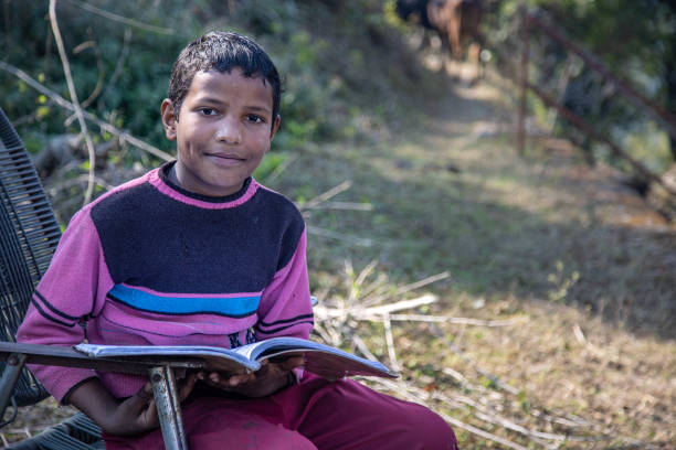 istock A young boy reading a book outdoors in a rural village setting on a sunny day 2179510622