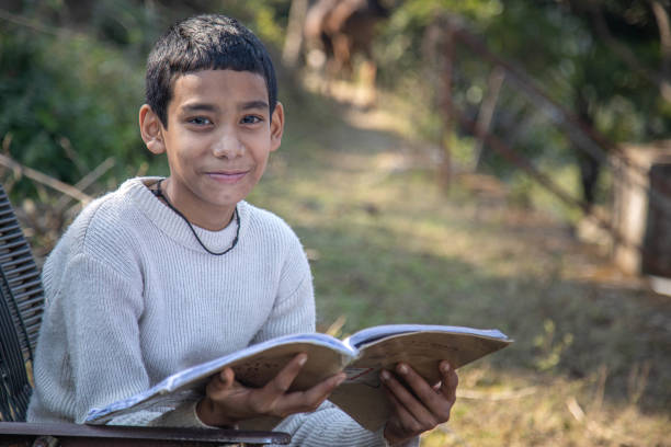 istock A young boy reading a book outdoors in a rural village setting on a sunny day 2179510662