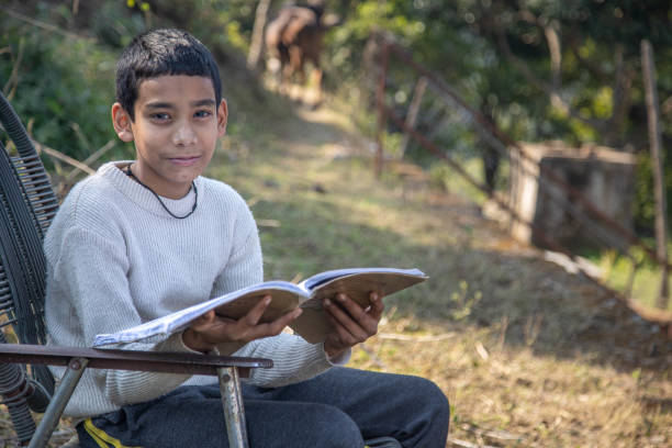 istock A young boy reading a book outdoors in a rural village setting on a sunny day 2179510681