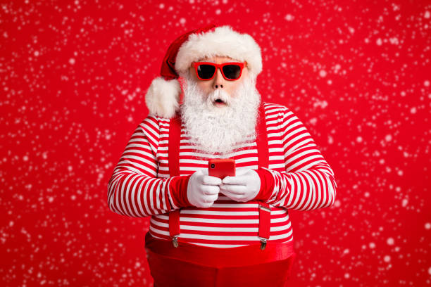 Portrait of his he nice handsome stunned amazed bearded fat gray-haired Santa using device app 5g order sale shopping web service isolated on bright vivid shine vibrant red color background