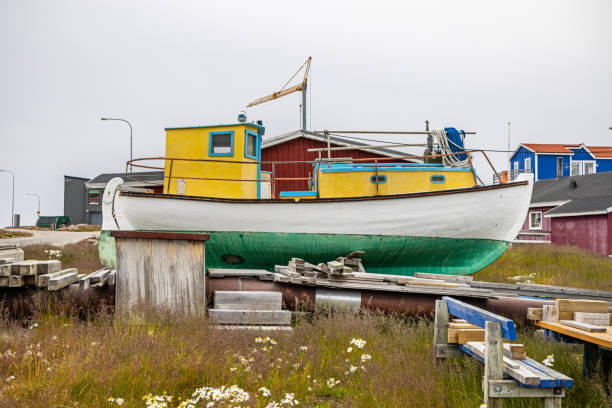 Ilulissat, Jakobshavn, Greenland, Denmark - August 22th 2024: Fishing boat placed on land in a residential district in preparation for the coming winter season
