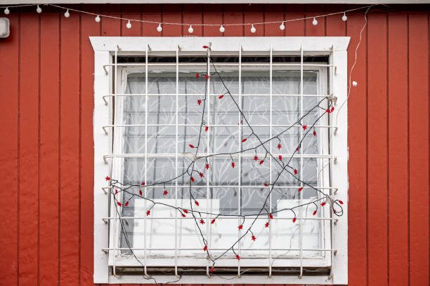 Ilulissat, Jakobshavn, Greenland, Denmark - August 29th 2024:  Window with a grate and Christmas lights in a traditional red wooden Greenlandic house