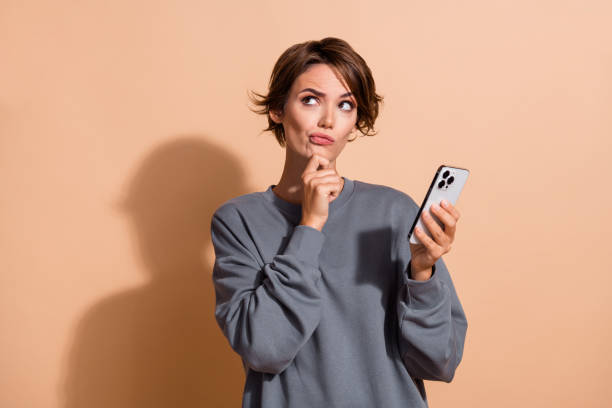 istock Photo of minded puzzled woman dressed grey pullover holding smartphone look at promo empty space isolated on pastel color background 2179525852