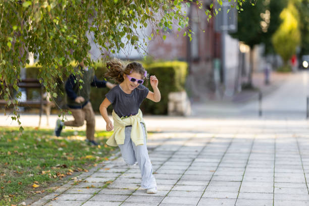 Cheerful brother and sister running in city park