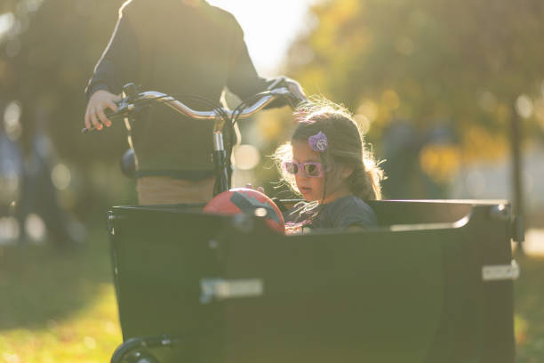 Brother riding his little sister in cargo bike in sunny autumn park