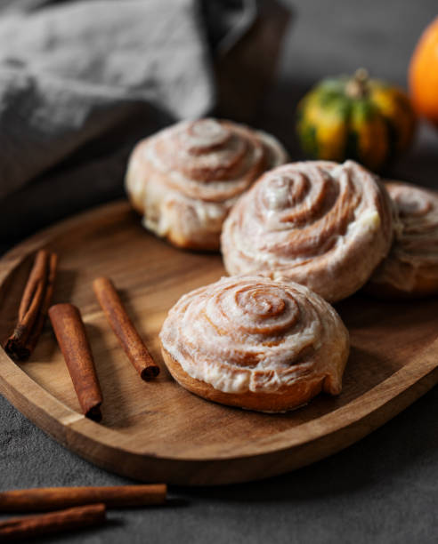 istock Sweet rolls with cinnamon and icing on a wooden board on a dark background. 2179529785