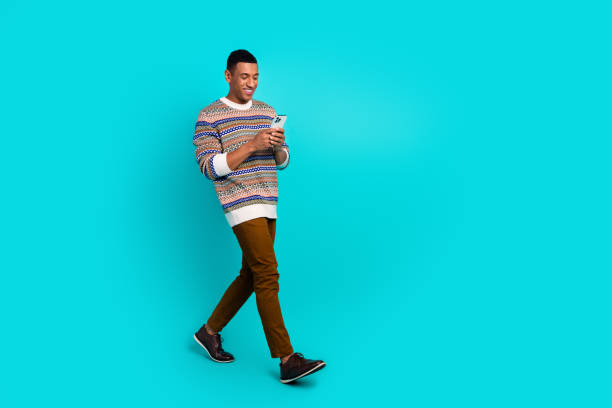 istock Full body portrait of nice young man walk empty space phone wear pullover isolated on turquoise color background 2179530397