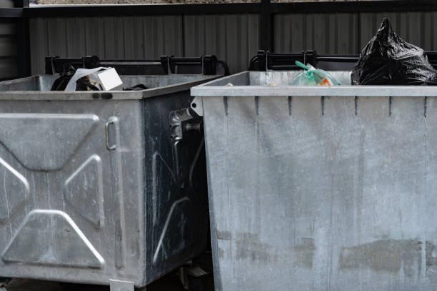 istock Two metallic garbage containers are positioned in a municipal area, overflowing with various types of waste, including bags and discarded items during daylight 2179532277
