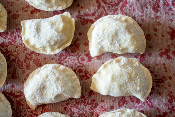 istock Handmade dumplings on a patterned cloth, ready for cooking. Traditional Polish cuisine showcasing a culinary art form. 2179534709