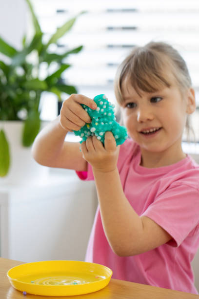 istock A cute girl playing with bright, blue slime, enjoying a fun and creative indoor activity. 2179539811