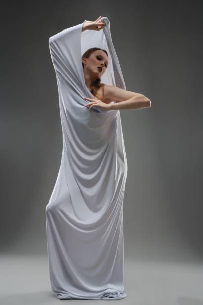 istock Elegant model posing in flowing white fabric against a neutral backdrop 2179542990