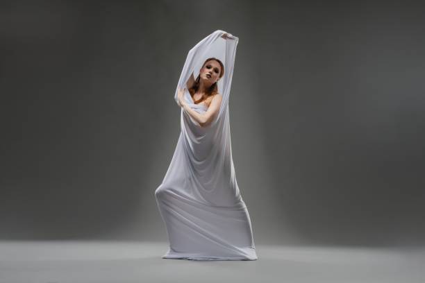 istock A dancer wearing a flowing white fabric performs a graceful pose indoors 2179543581