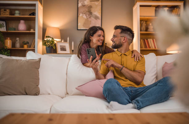 istock A loving couple is having crazy fun while using a mobile phone in the living room 2179544288